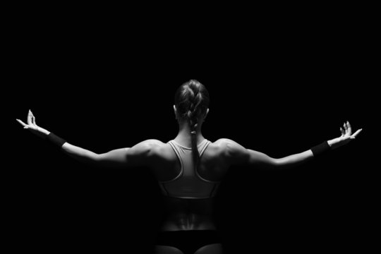 Photo of female athlete back towards you raising arms in the air from her sides